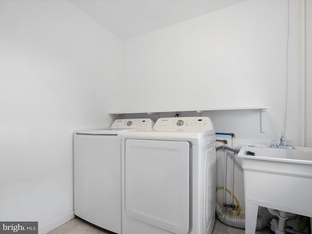 washroom with laundry area, washing machine and dryer, light tile patterned floors, and a sink