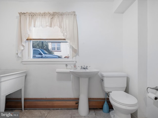 bathroom featuring baseboards, a sink, toilet, and tile patterned floors