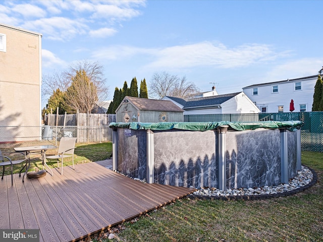 wooden terrace with a fenced in pool, an outbuilding, a yard, a shed, and a fenced backyard