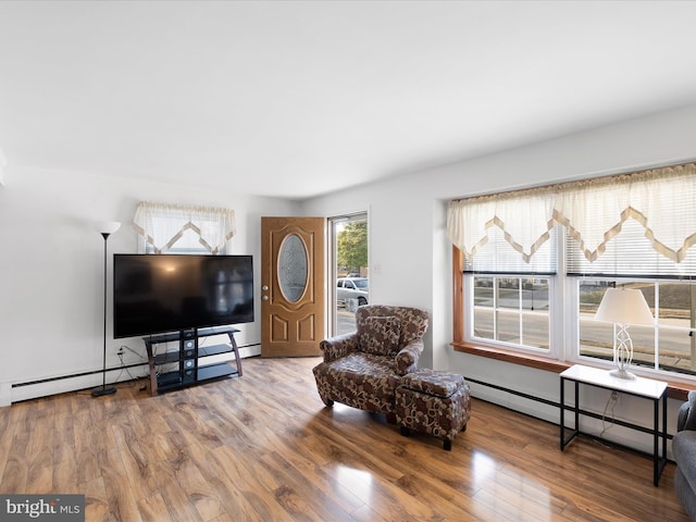 living area featuring a baseboard heating unit and wood finished floors