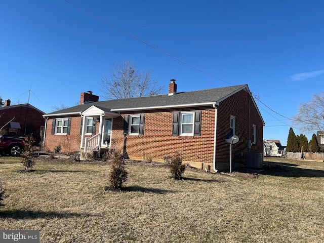 view of front facade featuring brick siding, a front lawn, a chimney, and cooling unit