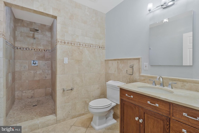 bathroom featuring toilet, a tile shower, tile walls, and tile patterned floors