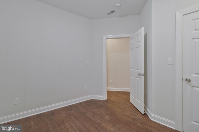 unfurnished bedroom with visible vents, dark wood finished floors, and baseboards