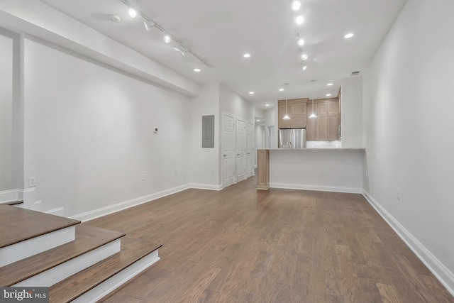 unfurnished living room featuring recessed lighting, electric panel, baseboards, and wood finished floors