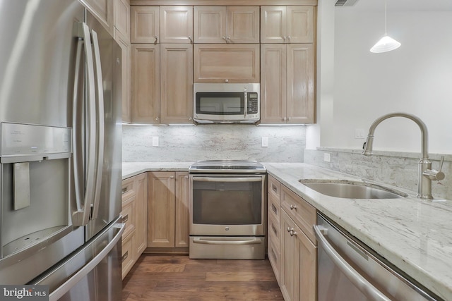 kitchen featuring decorative backsplash, dark wood-style floors, light stone counters, appliances with stainless steel finishes, and a sink