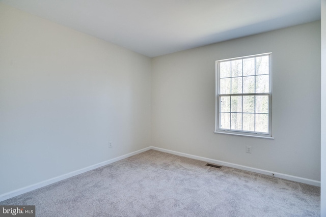 carpeted spare room with visible vents and baseboards