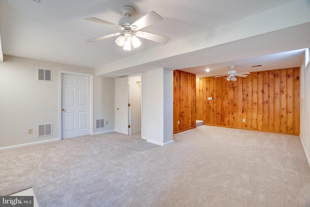 finished below grade area with wooden walls, visible vents, and light carpet