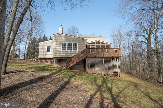 back of house featuring stairway, a wooden deck, a chimney, a yard, and a sunroom