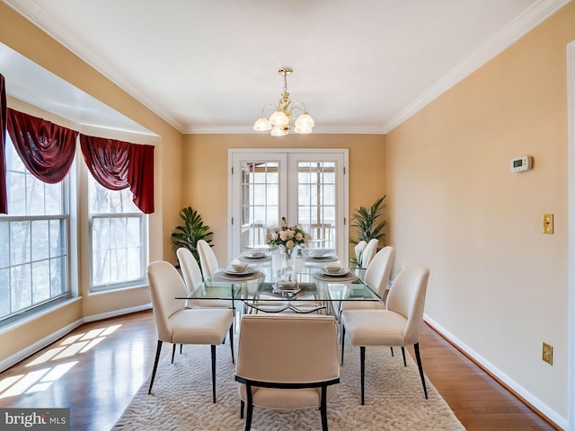 dining space featuring baseboards, a chandelier, ornamental molding, french doors, and wood finished floors