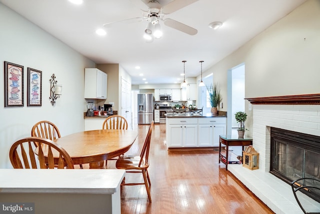 dining space featuring recessed lighting, a fireplace, light wood-type flooring, and ceiling fan