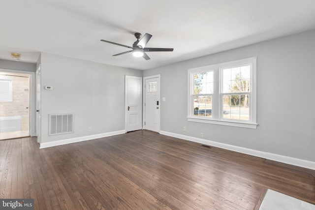 unfurnished living room with dark wood-style floors, baseboards, visible vents, and a ceiling fan