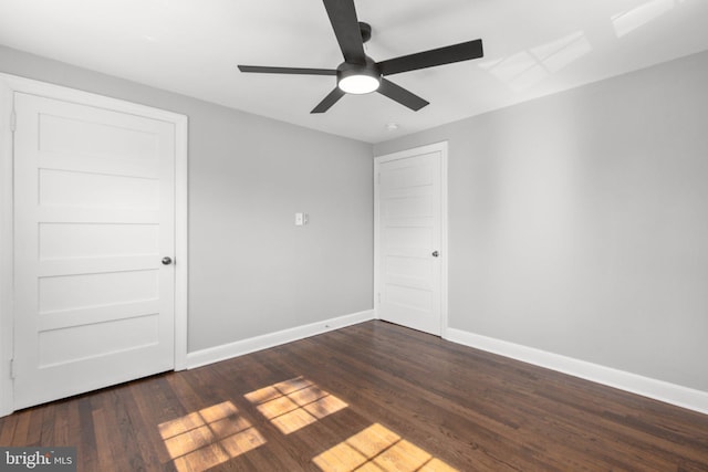 spare room with dark wood-style floors, ceiling fan, and baseboards