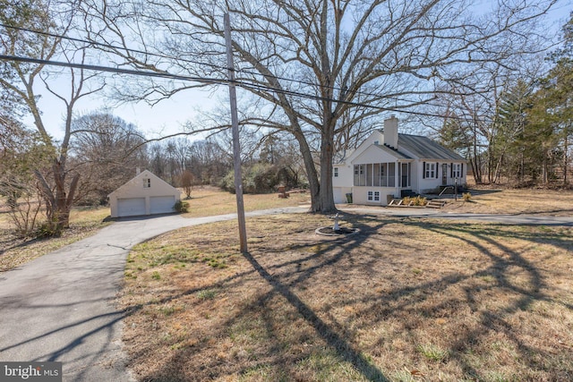 view of front facade with a garage, an outbuilding, a chimney, and a front lawn