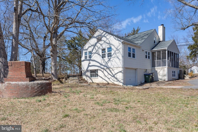 view of home's exterior with an attached garage, a sunroom, a lawn, stairway, and a chimney