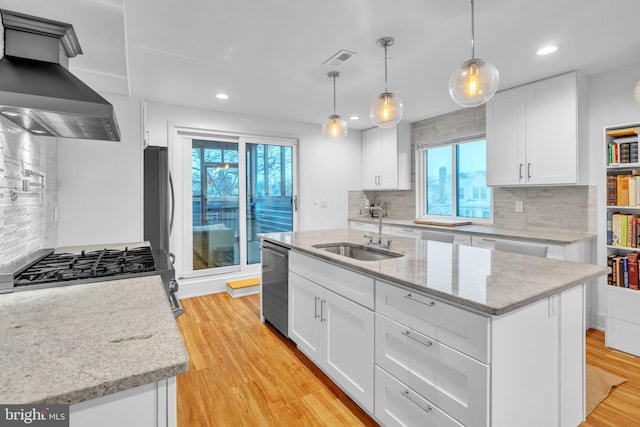 5664 Gainor Rd, Philadelphia, PA 19131 - kitchen with light wood finished floors, stainless steel appliances, wall chimney range hood, white cabinetry, and a sink