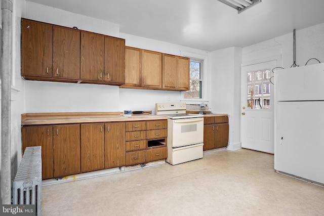 kitchen featuring white appliances, light countertops, radiator, light floors, and brown cabinetry