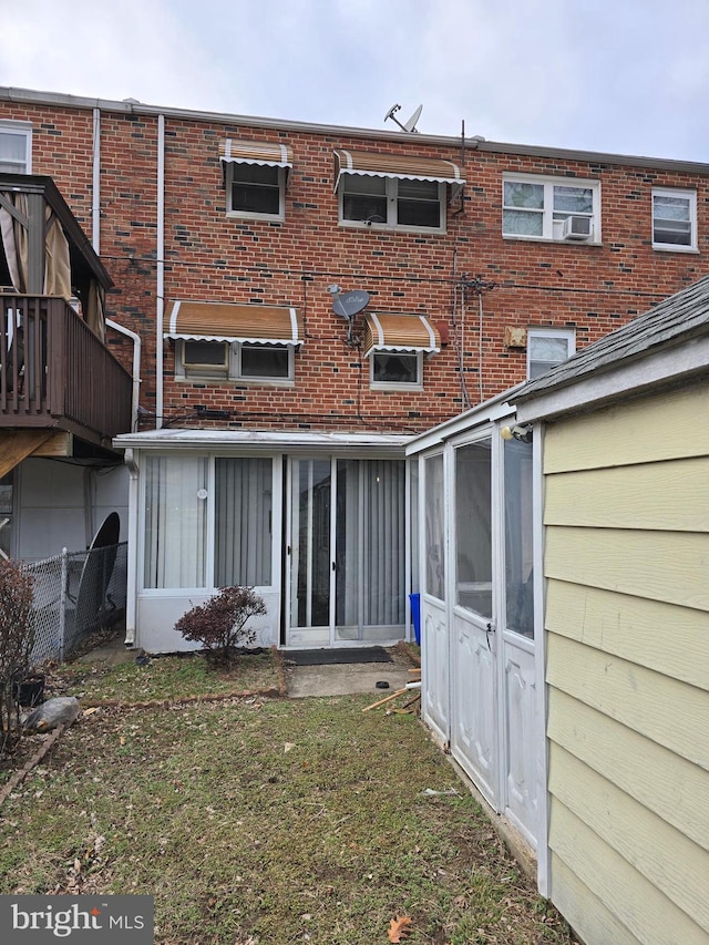 back of house with brick siding, a lawn, and fence