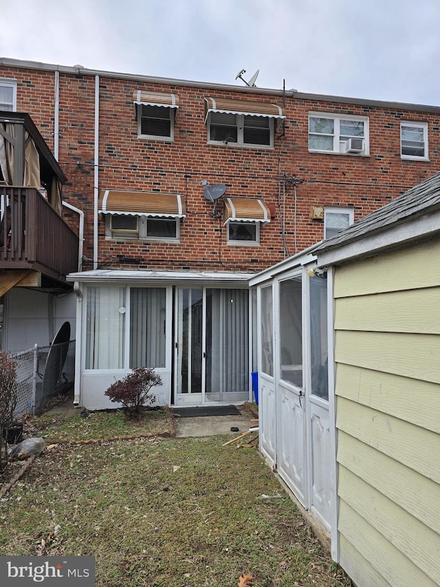 rear view of house with a yard, brick siding, and fence