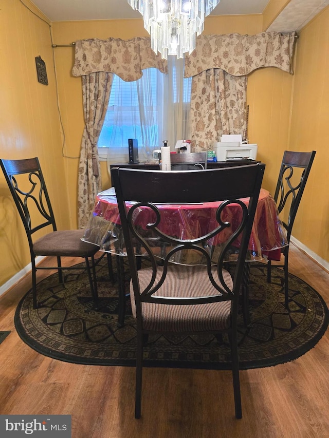 dining area with baseboards, a notable chandelier, and wood finished floors