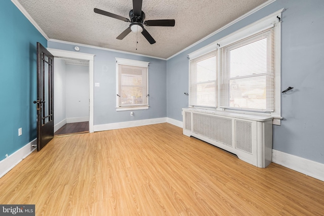 spare room with a textured ceiling, radiator heating unit, wood finished floors, and crown molding