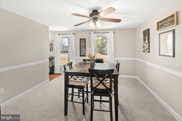 dining area featuring light colored carpet, baseboards, and ceiling fan