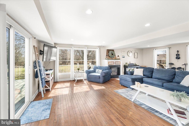 living room with hardwood / wood-style floors, a glass covered fireplace, and recessed lighting