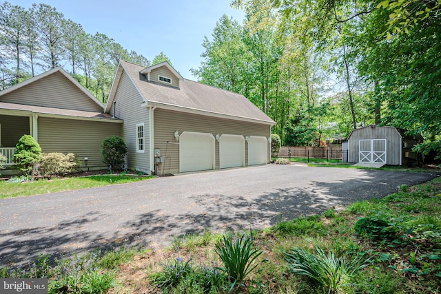 17024 Turtle Hl, Milford, DE 19963 - view of side of home featuring fence, a shingled roof, aphalt driveway, a garage, and a storage shed