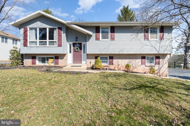 raised ranch featuring brick siding and a front yard