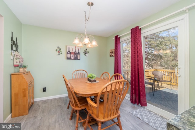 dining area with light wood-type flooring, baseboards, and an inviting chandelier