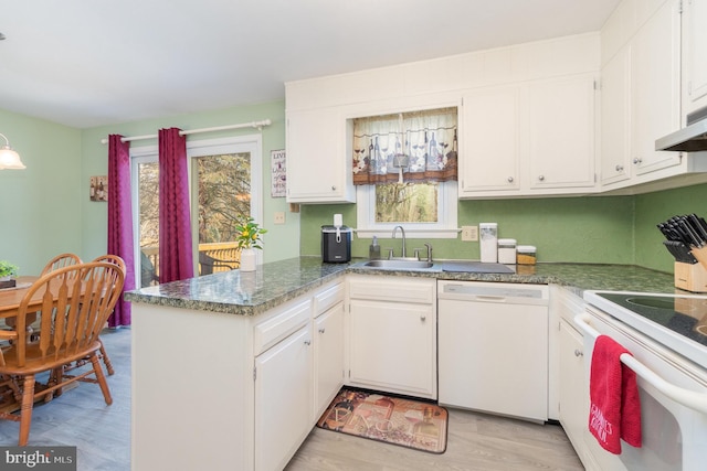 kitchen with a wealth of natural light, white appliances, a peninsula, and a sink