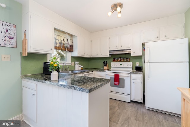 kitchen with white appliances, a peninsula, white cabinets, under cabinet range hood, and dark countertops