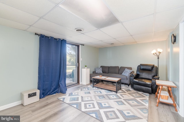 living room with visible vents, a paneled ceiling, baseboards, and wood finished floors