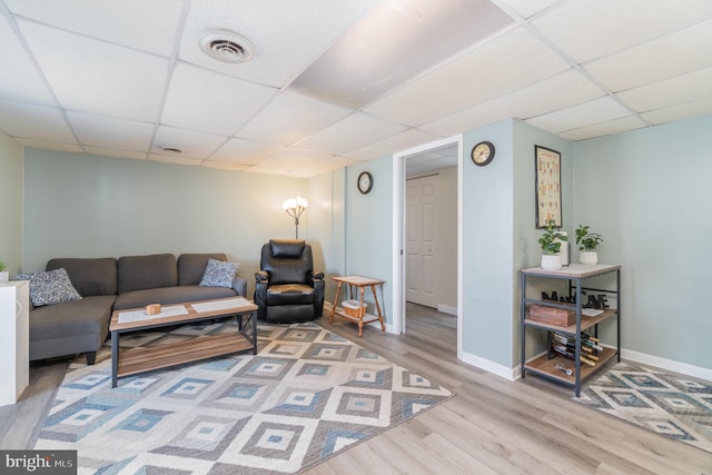 living room with wood finished floors, a paneled ceiling, visible vents, and baseboards