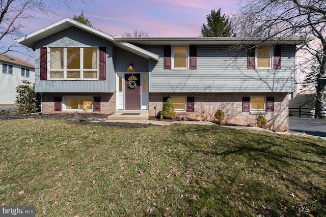 bi-level home with a front yard and brick siding