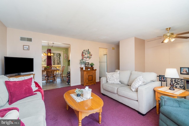 living area featuring visible vents, baseboards, and ceiling fan with notable chandelier