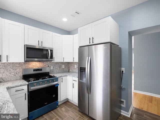 kitchen with wood tiled floor, visible vents, stainless steel appliances, and backsplash