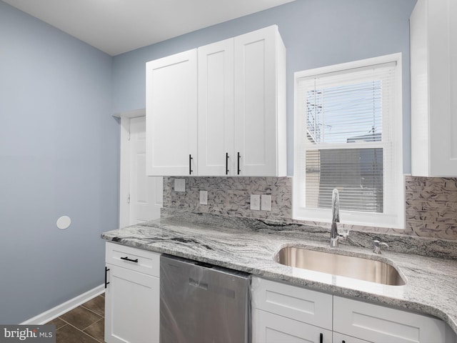 kitchen with white cabinetry, a sink, backsplash, and stainless steel dishwasher