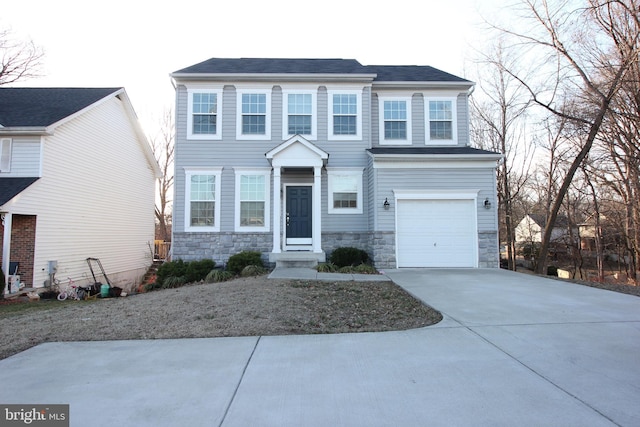 colonial house featuring a garage, stone siding, and concrete driveway