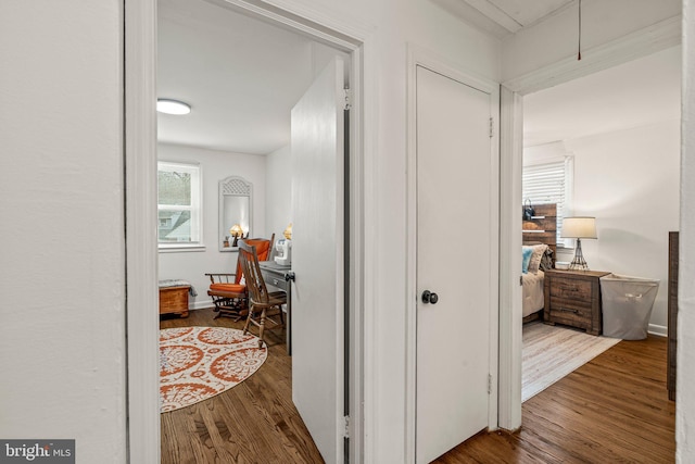 corridor featuring attic access, baseboards, and wood finished floors