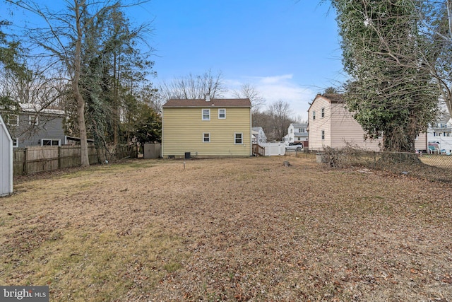 rear view of property featuring a fenced backyard and a lawn