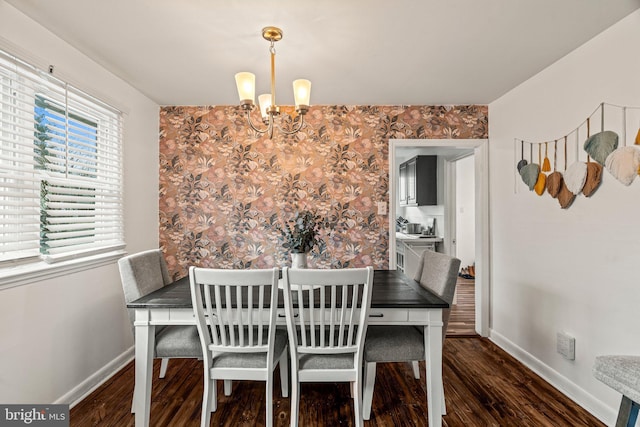 dining space featuring a notable chandelier, wallpapered walls, wood finished floors, and baseboards