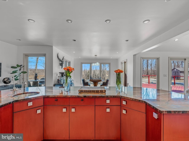 kitchen with red cabinetry, open floor plan, a sink, and recessed lighting