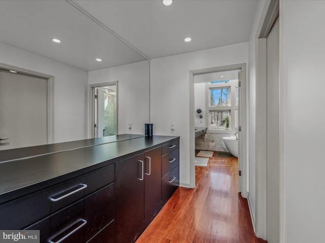 full bath with a freestanding bath, vanity, hardwood / wood-style flooring, and recessed lighting