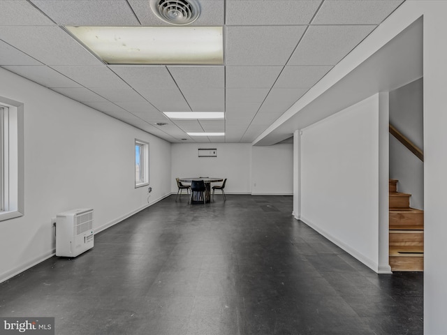 below grade area with stairs, a drop ceiling, visible vents, and baseboards