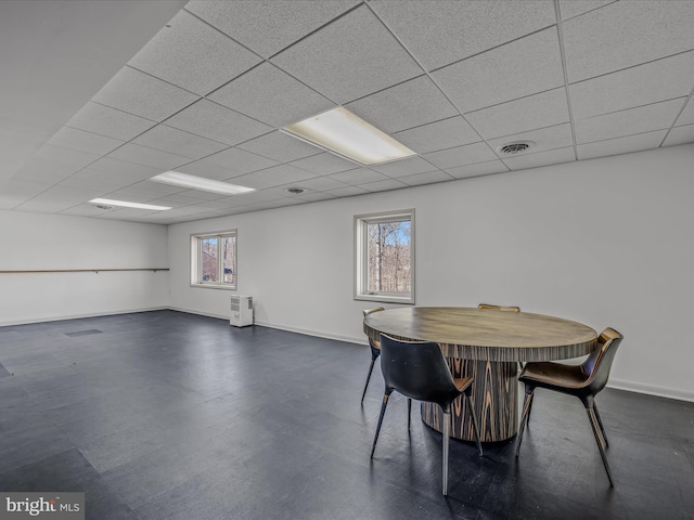 dining room with visible vents, concrete floors, a drop ceiling, and baseboards