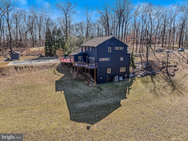 rear view of property featuring a storage shed, a deck, a lawn, and an outbuilding