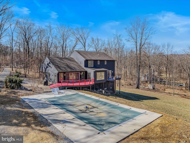 back of property featuring a covered pool, a yard, and a deck