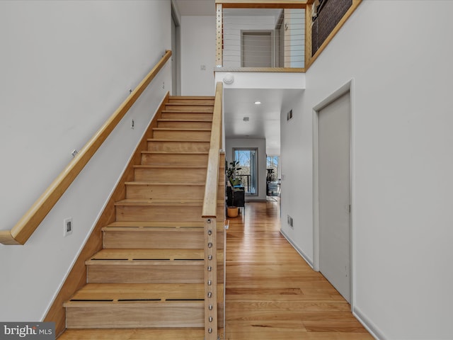 stairs featuring visible vents, a towering ceiling, and wood finished floors