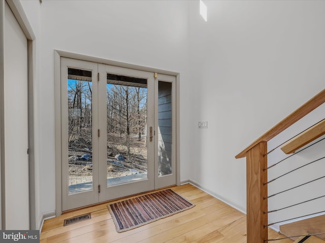 doorway featuring a wealth of natural light, wood-type flooring, visible vents, and baseboards