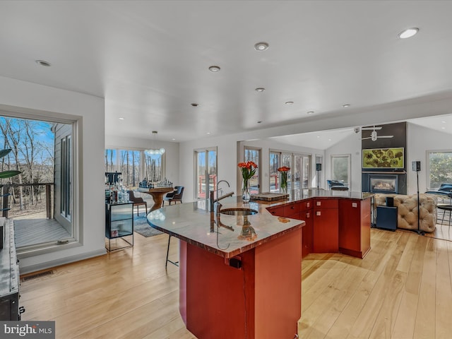 kitchen with light wood-type flooring, visible vents, open floor plan, and a sink